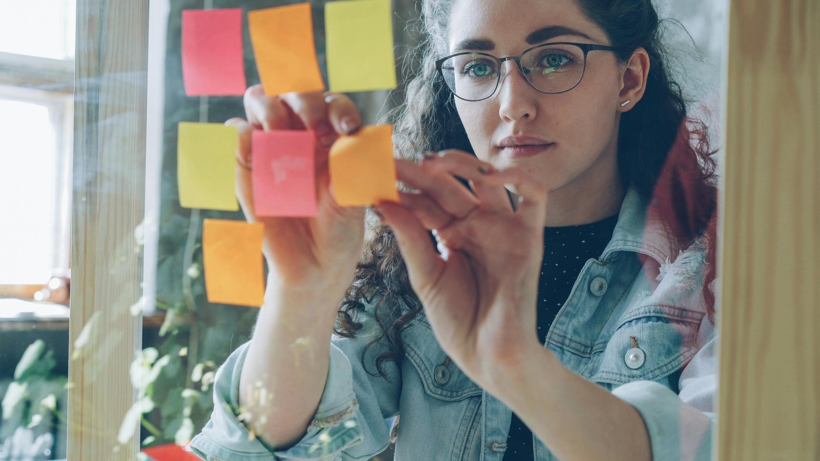 Jeune femme devant un mur de post-it colorés représentant des choix multiples